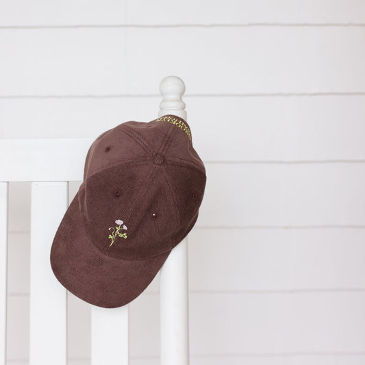 Brown cap with floral design on a white wooden surface