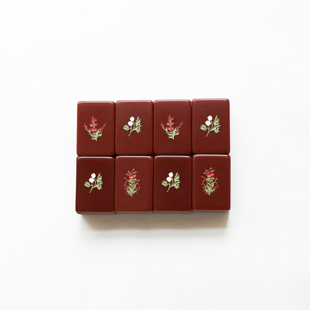 Set of red mahjong tiles with floral designs on a white background